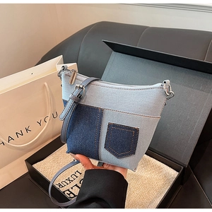 Detail der Denim-Patchwork-Schultertasche mit Lederriemen und silbernem Reißverschluss