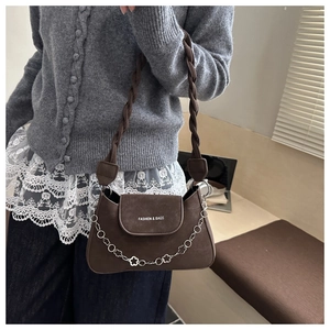 Detail of dark brown matte leather bag with woven strap and silver flower chain decoration