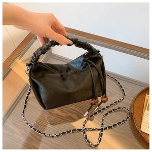 Détail du sac à main noir à poignée plissée avec perles ambre et chaîne argentée