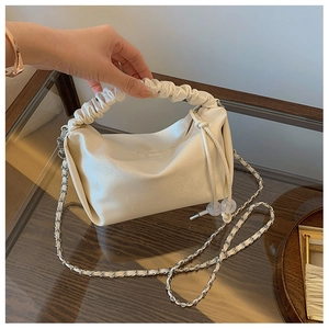 Détail de la poignée froncée et du cuir végan à texture florale du sac crème