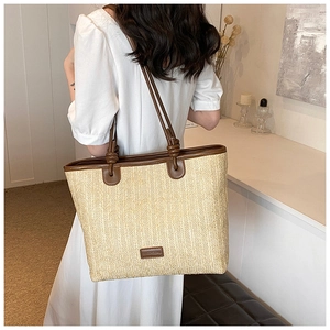 Close-up of woven straw bag with dark brown leather straps and visible texture