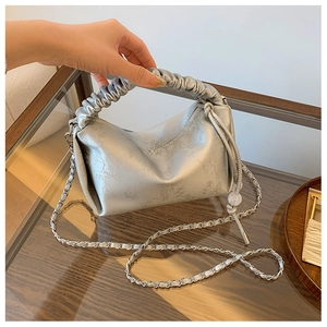 Détail du sac à main plissé argenté avec texture florale, poignée froncée et bandoulière