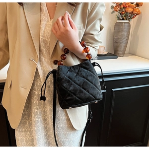 Détail du sac seau en velours matelassé avec anse en perles ambrées et bandoulière