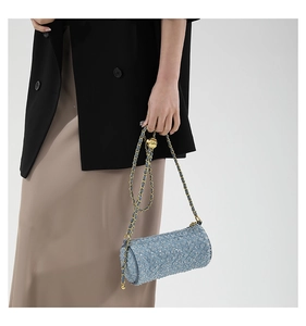 Détail du sac cylindre en tweed bleu clair avec chaîne dorée et boule en métal réglable