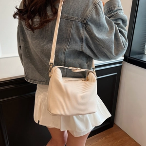 Sac à bandoulière en velours côtelé blanc porté par un mannequin, style minimaliste