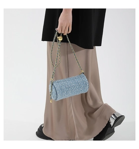 Détail macro du sac cylindre en tweed bleu avec paillettes et bandoulière dorée