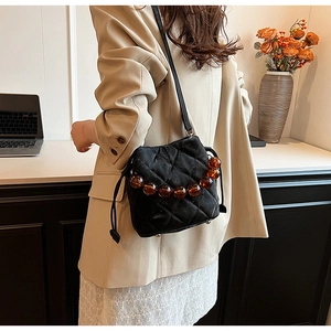 Détail du sac seau noir matelassé avec poignée en perles d'ambre et cordon de serrage