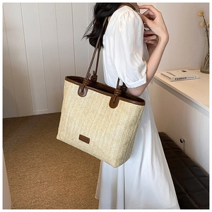 Detail of woven straw tote bag with brown leather handles and decorative knots