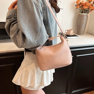 Sac à bandoulière plissé rose en cuir avec boucles dorées porté par un mannequin