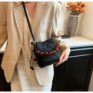 Détail du sac seau noir matelassé avec poignée en perles d'ambre et cordon de serrage