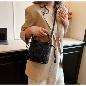 Détail du sac seau matelassé noir avec poignée en perles d'ambre et fermeture par cordon