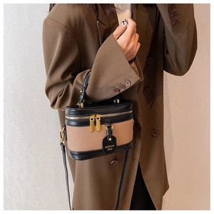Gros plan d'un sac bandoulière en toile beige et cuir noir avec double fermeture éclair