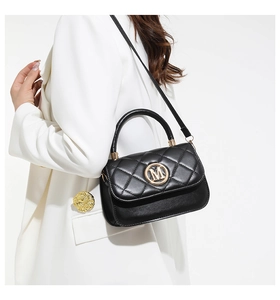 Détail du sac à main en cuir matelassé noir avec logo M doré et poignée ronde chic