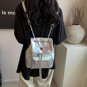 Holographic silver backpack with metal chains and heart detail worn by a model
