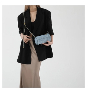 Détail d'un sac cylindrique en tweed bleu clair avec bandoulière chaîne dorée sur mannequin