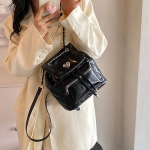 Quilted black shiny backpack with heart buckle and metal chain straps on model