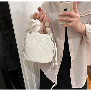 Détail du sac seau matelassé blanc avec une grande poignée en perles et cordon de serrage