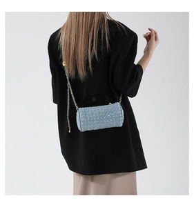 Gros plan du sac cylindre en tweed bleu clair avec bandoulière chaîne dorée chic