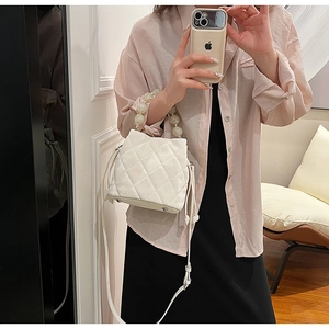 Détail d'un sac seau blanc matelassé avec poignée en perles et bandoulière amovible
