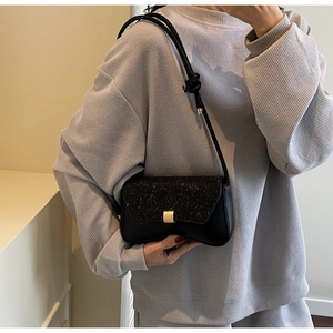 Détail du sac sous l'aisselle à paillettes noires avec boucle dorée sur un mannequin