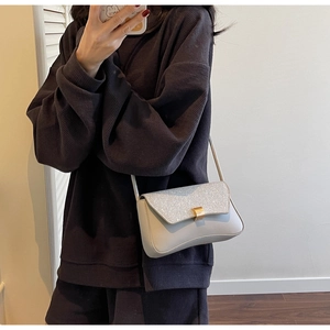 Close-up of the grey crossbody bag featuring a sparkling silver glitter flap and gold buckle
