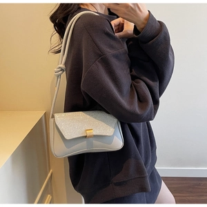 Detailed view of grey shoulder bag with sparkling rhinestone flap and golden lock