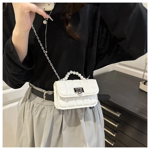 Close-up of white quilted mini bag with pearl handle and silver chain strap details