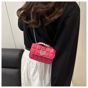 Detail of rose red quilted mini bag with pearl handle and silver chain strap