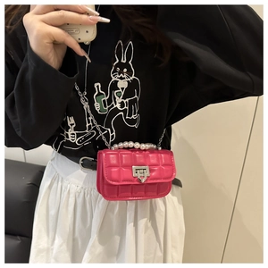 Close-up of pink quilted crossbody bag featuring a pearl handle and gold chain strap