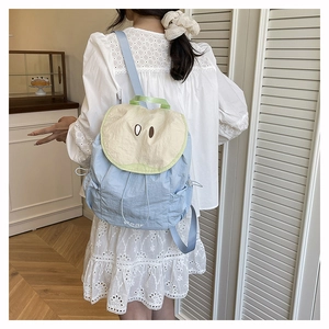 Rear view of a light blue macaron backpack with cute cartoon eyes on white lace dress