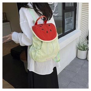 Detail of watermelon-shaped backpack showing red seed pattern and green nylon fabric texture