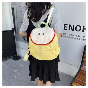 Close-up of a cute yellow apple-shaped backpack featuring creative fruit embroidery and nylon texture