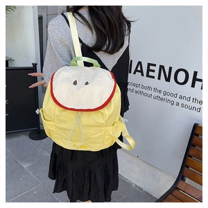 Detail of creative yellow apple-shaped backpack with red sliced apple design and side pocket