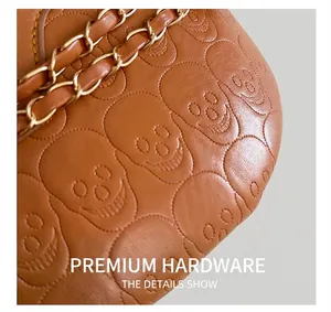 Detailed macro of brown leather shoulder bag with skull embossing and gold metal chain