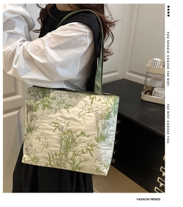 Détail du sac fourre-tout crème avec motif bambou vert porté à l'épaule par un mannequin