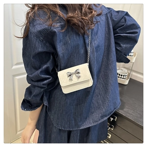 Close-up of a white mini square bag with a silver bow and metal chain strap