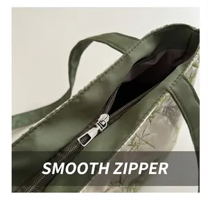 Détail de la fermeture éclair argentée et broderie bambou verte sur un sac cabas blanc