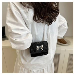 Close-up of black snakeskin texture mini bag with silver bow buckle and chain strap