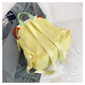 Dettaglio dello zaino in nylon giallo con manici verdi e finiture arancioni