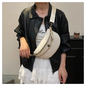 Detail of white moon-shaped crossbody bag with embossed texture and gold chain strap