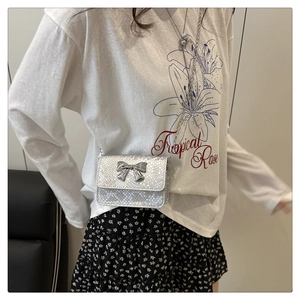 Silver snakeskin crossbody mini bag with bow clasp worn by model for style and size