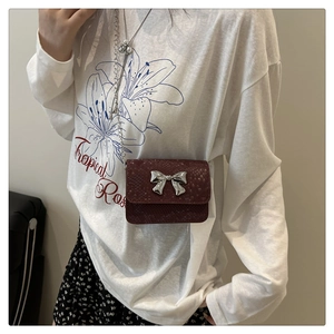 Detailed macro view of dark red crocodile textured leather mini bag with silver bow
