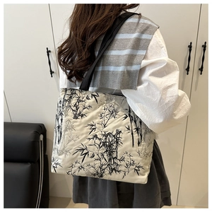 Gros plan d'un sac cabas en toile avec peinture de bambou porté sur l'épaule de côté