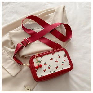 Detalle del bolso bandolera con estampado de cerezas, herrajes dorados y colgante