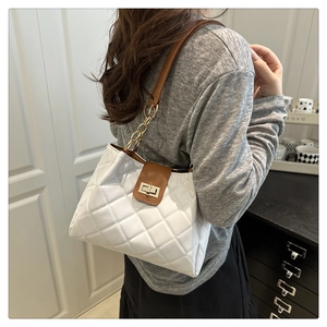 Detail of white quilted tote bag with brown flap, gold chain strap and metal clasp closure