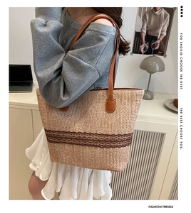Close-up of woven straw tote bag featuring brown lace details and leather handles