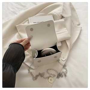 Interior detail of a white minimalist small square bag showing capacity for cosmetics