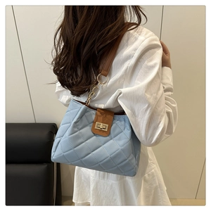 Détail du sac à bandoulière matelassé bleu clair avec lanière en cuir brun et chaîne dorée