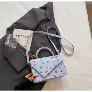 Détail du petit sac bleu clair avec imprimé cerises et poignée spirale élégante