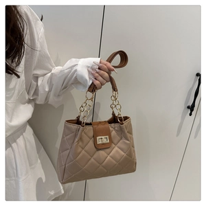 Detalle de bolso acolchado con asa de cadena dorada y cierre giratorio de metal